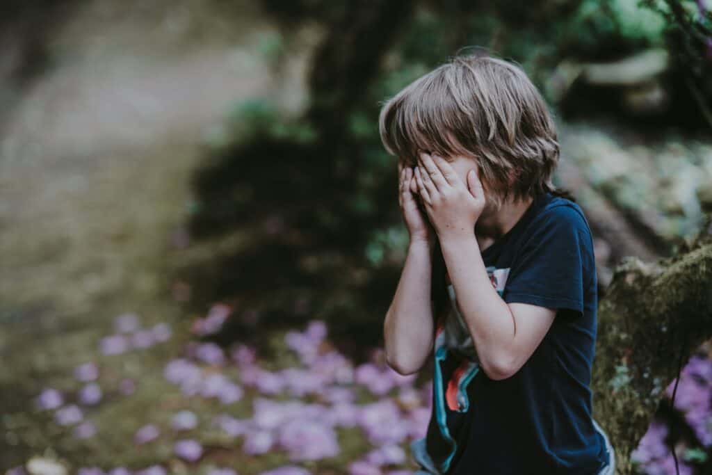 young boy covering his eyes