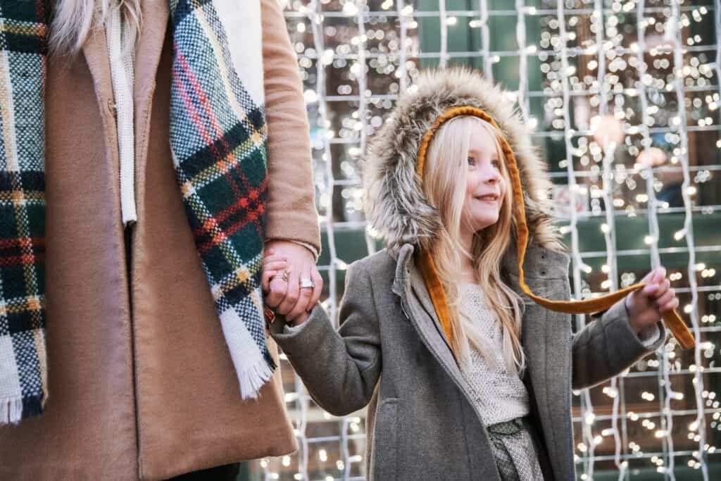 Girl holding adult hand looking at lights