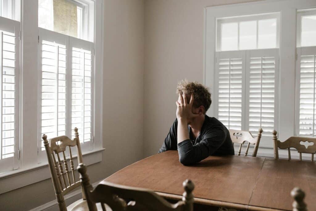 man in dining room with face in hand