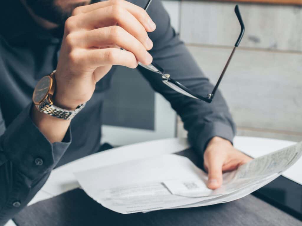man holding glasses and pile of bills