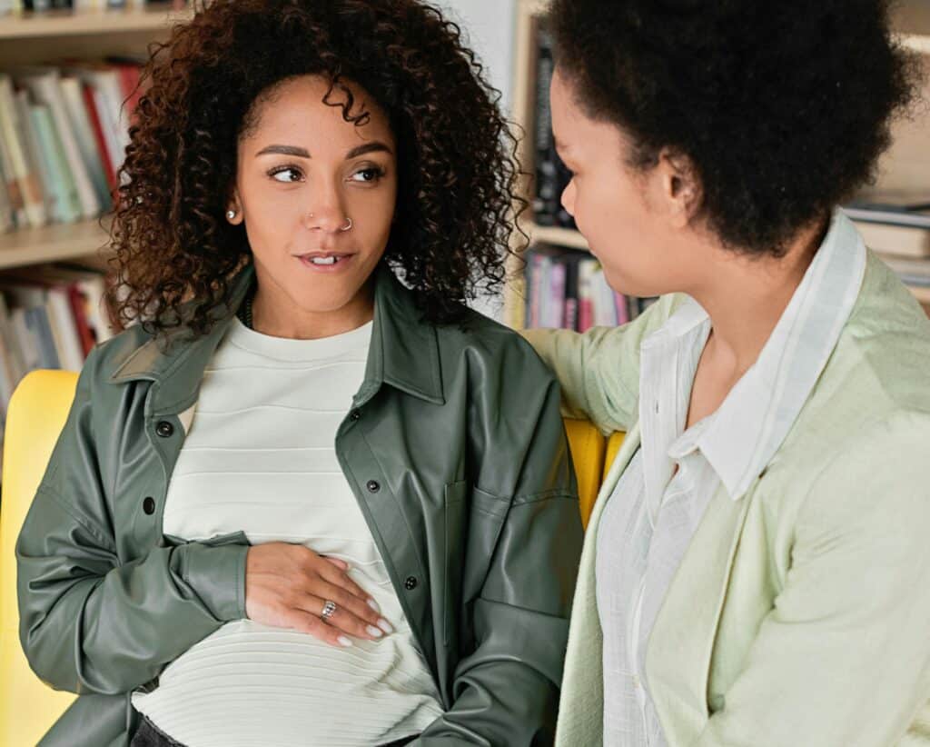 Pregnant woman and other woman mom arm around her