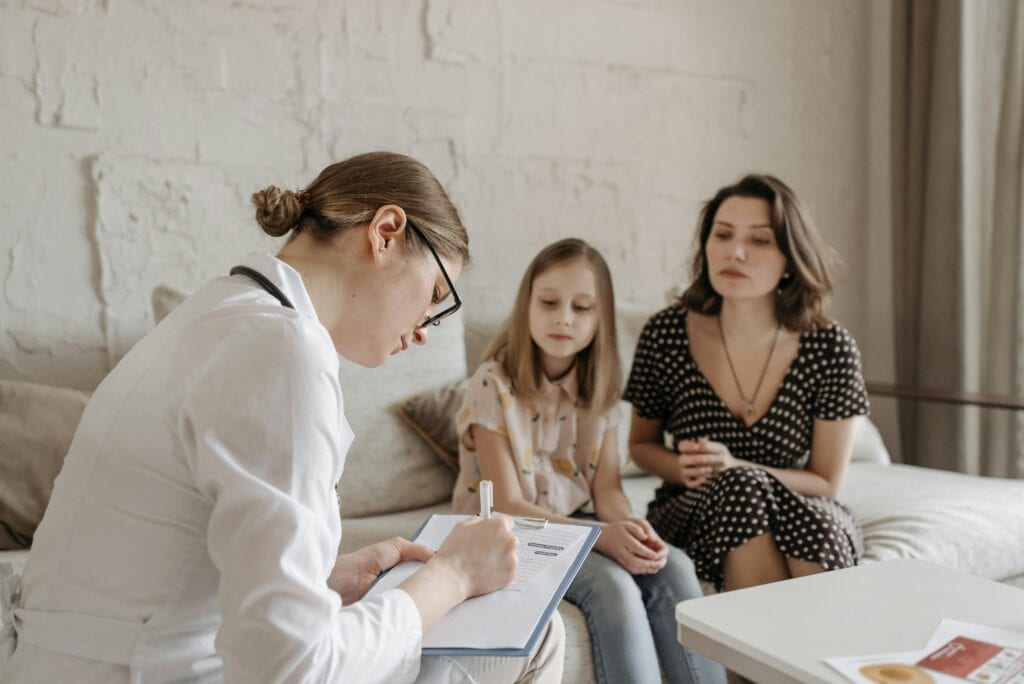 mom and young teen daughter with physician in waiting room