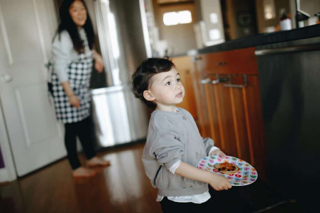 Preschool boy holding plate pregnant mom in background