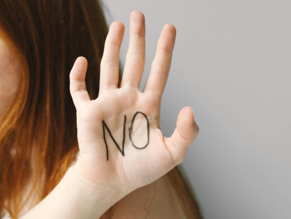 girl holding up hand with NO written on it