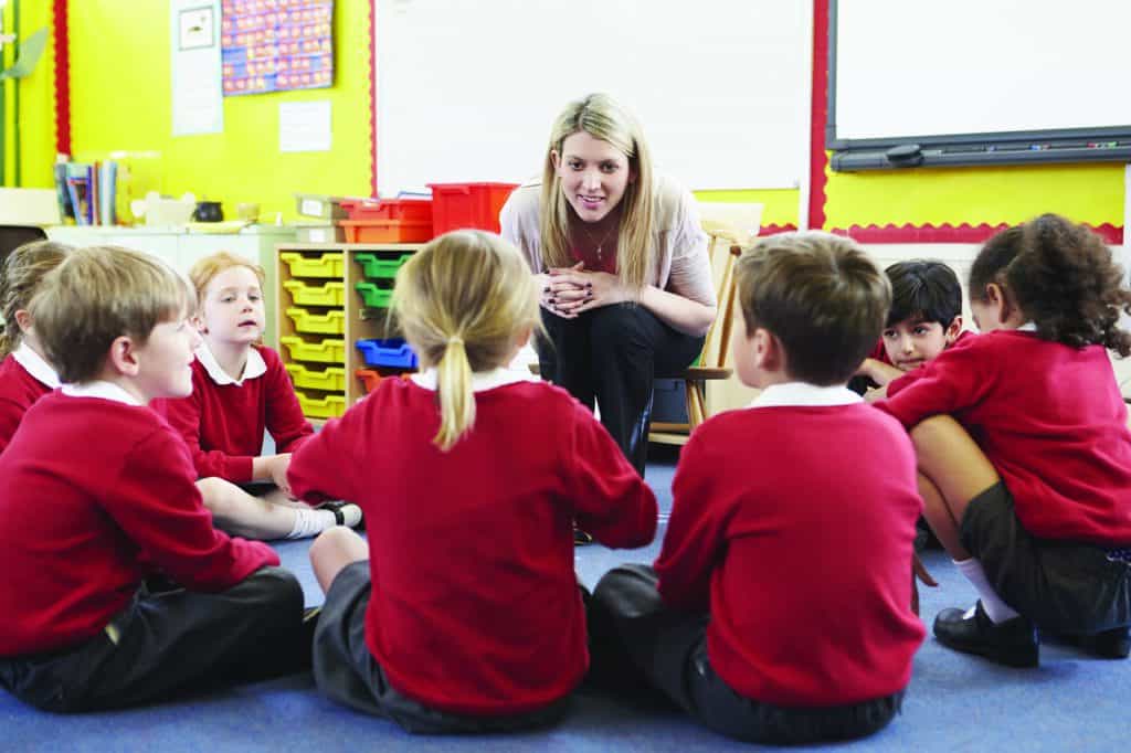Teacher talking to young children in school uniforms
