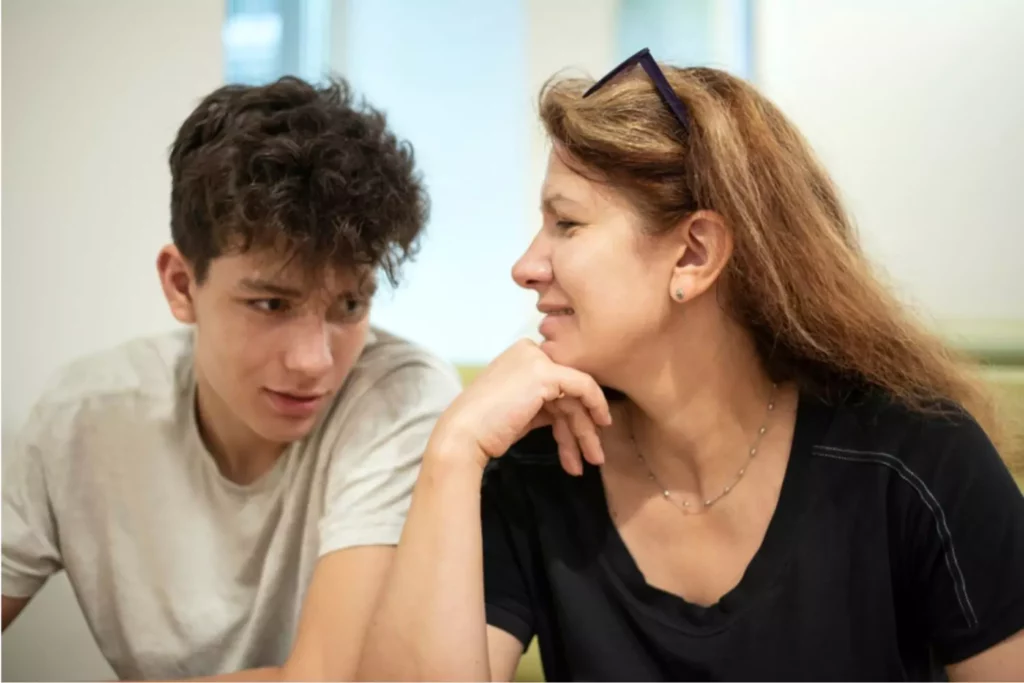 Mom and teen boy sitting on couch and having a conversation