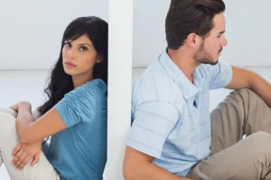 A couple sitting back-to-back separated by a wall, portraying the emotional disconnect often felt when your spouse is emotionally distant.