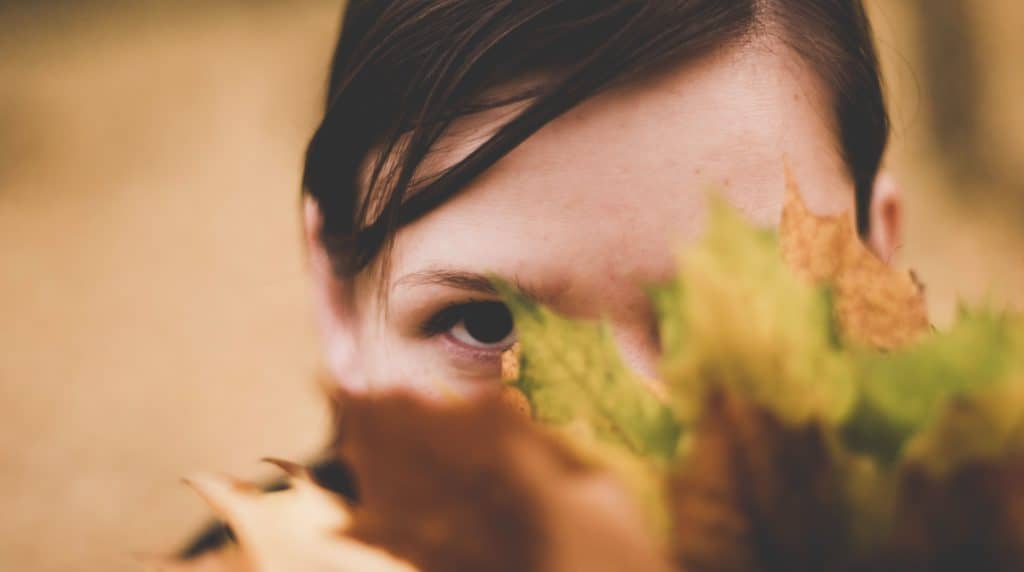Shy child hiding behind leaves
