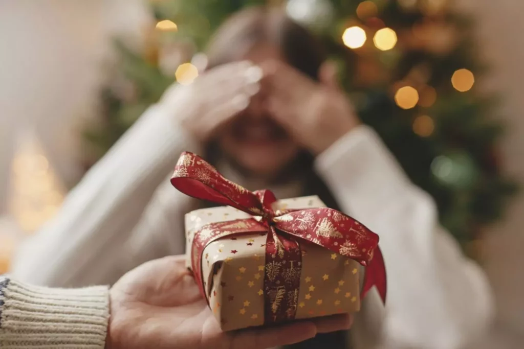 Little girl closing her eyes ,being handed a Christmas present